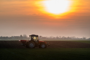 Obraz premium Farmer with tractor seeding - sowing crops at agricultural fields