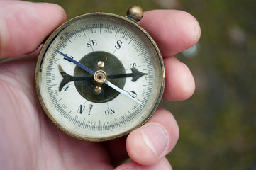Traveler holding compass in hand. Compass in a hand blurred background