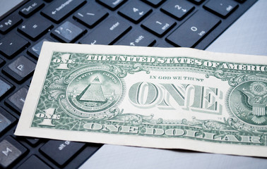 one dollar on the black computer keyboard