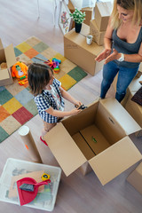 Aerial view of unrecognizable mother and son unpacking moving box