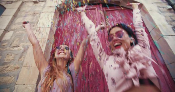 Beautiful young women throwing confetti in old city streets