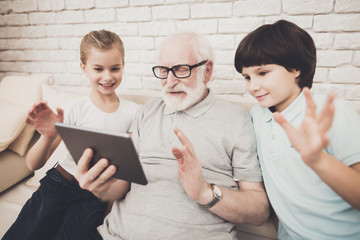 Grandfather, grandson and granddaughter at home. Grandpa and children are taking selfie.