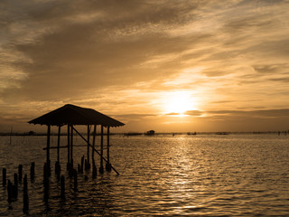 Fototapeta na wymiar Beautiful sunset landscape orange golden sky above sea with silhouette of fish farms.