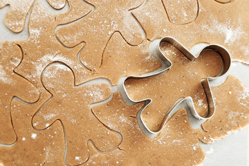 Gingerbread Cookie. New Year figures from a dough, prepared for baking in the oven. Cookies in the form of Gingerbread man on paper for baking. Christmas food concept.