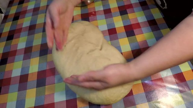 This is footage of female hands or a woman massing a dough into shape ready to bake some bread. Home-made cooking video for any need.