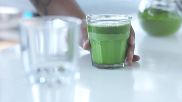 male hand puts a glas with matcha late on bar table