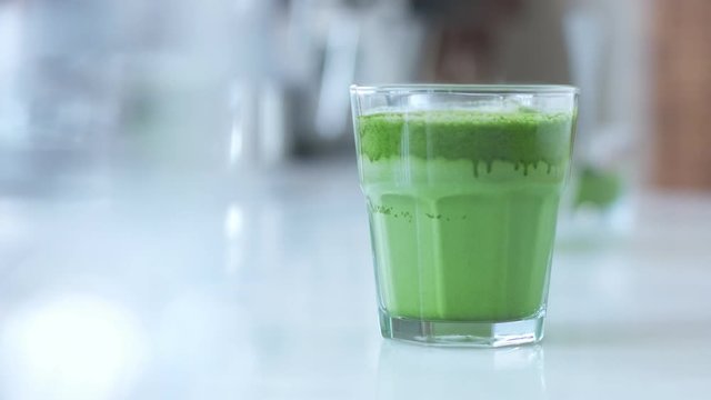 male hand puts a glas with matcha late on bar table