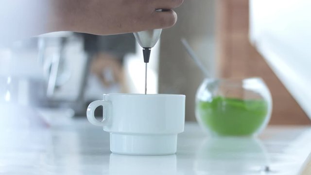 mixing matcha tee with water in white cup