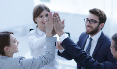 successful business team giving each other a high-five, standing in the office