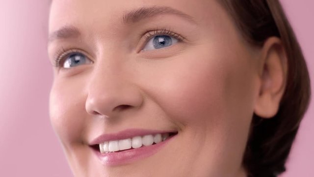 closeup of woman on pink background smiling Blue eyed woman with ideal skin