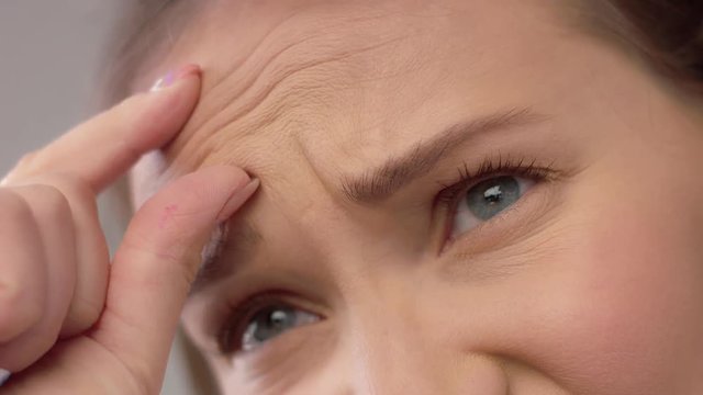 Disappointed young woman showing wrinkles en her forehead. Age effects on young skin