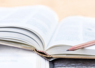 Open textbook stacked on the wooden table. selective focus.