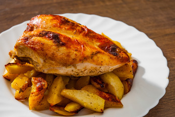 roasted chicken breast with potato in a plate on wooden table