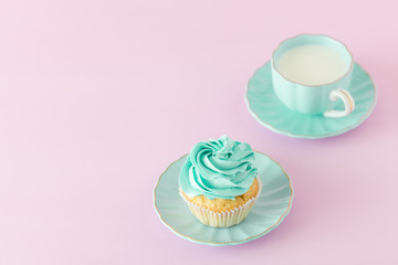 Cupcake with mint cream decoration and cup of milk and coffe on pink pastel background. Mother's day greeting card