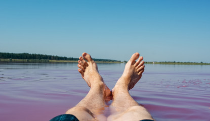 Close-up view of man's legs and feet in pink lake