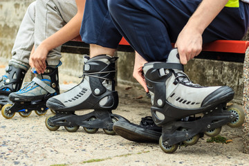 People friends putting on roller skates outdoor.