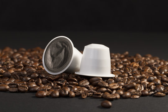 Close up on coffee capsule resting on roasted coffee beans