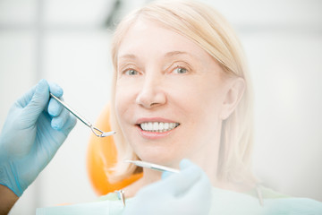 Happy woman looking at camera with toothy smile while visiting her dentist for check-up