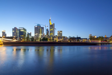 Fototapeta na wymiar Bankenviertel von Frankfurt in der Abenddämmerung mit vorbeifahrendem Schiff