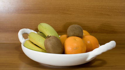 Fruit bowl with bananas oranges and kiwi on a table