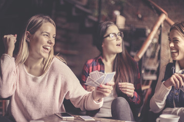  Cheerful three girls at home playing cards.