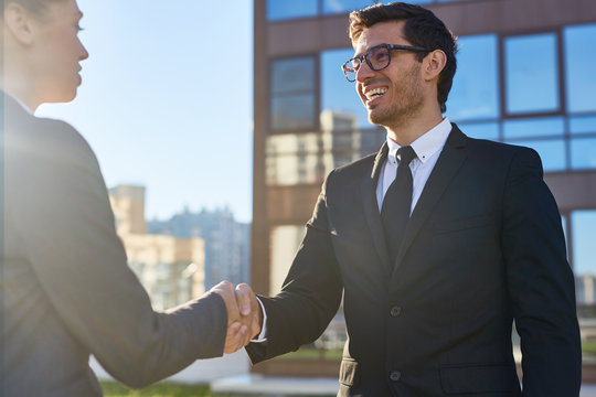 Successful agent or broker greeting his client by handshake after signing contract