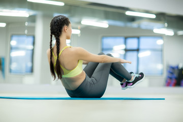 Fototapeta premium Young female doing exercise for belly muscles on the floor during workout