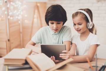 Children at home. Brother and sister are using tablet doing homework.