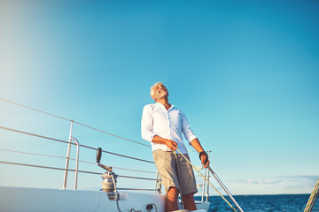 Mature man looking skyward while out sailing on his boat