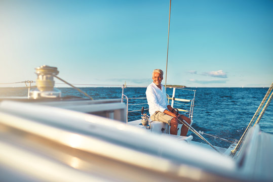 Smiling mature man sailing his yacht at sea