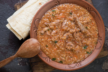 Clay plate of traditional georgian soup kharcho with lavash, view from above