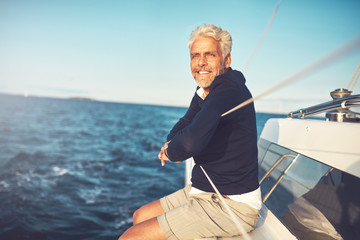 Smiling mature man admiring the sea view from his sailboat