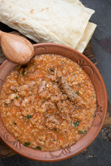 Georgian traditional kharcho soup with lamb meat and rice served in a clay plate, vertical shot, flat-lay