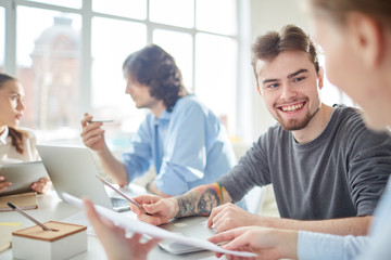 Happy casual businessman working in team with his coworkers at meeting