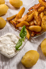 Roasted potatoes with herb sauce in glass dish placed on wooden table traditional European food