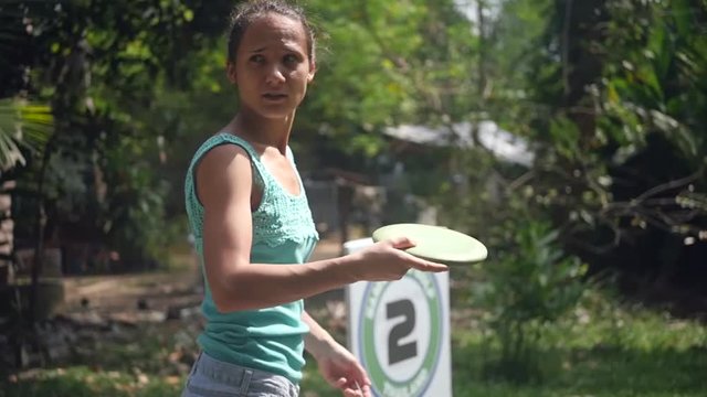 Slim girl athlete learns to play frisbee golf in the park, swinging for a throw. slow motion, 1920x1080, full hd