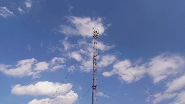 GSM or CDMA Antenna on a blue sky background, timelapse.