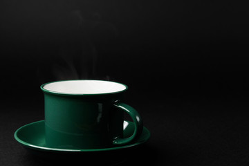 strong black coffee in a mug of emerald color on a black matte background
