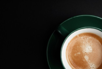 strong black coffee in a mug of emerald color on a black matte background