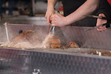 man carving pork joint with fork and knife at hog roast