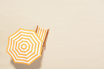 The concept of summer vacation. Top view on a sun lounger under an umbrella on the sandy beach