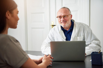 Obraz premium Senior doctor talking to young woman in clinic