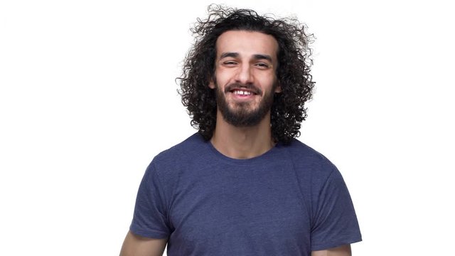Portrait of brazilian guy in basic clothing smiling and touching his curly dark hair, isolated over white background. Concept of emotions
