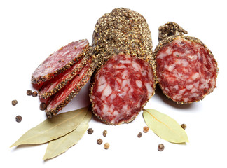 Dried organic salami sausage covered with pepper on white background