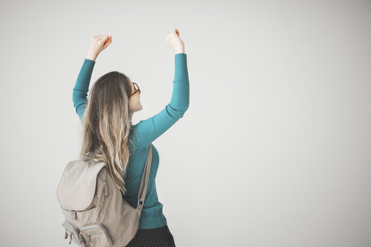 Female student arms raised with backpack on grey background