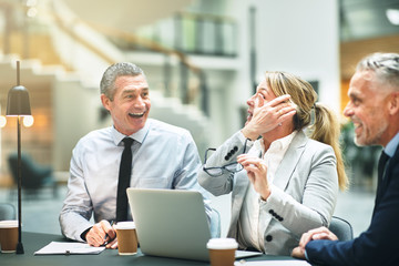 Mature businesspeople laughing while sitting together at an offi