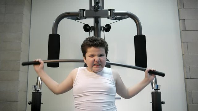 thick angry kid boy trains in gym fat burning.will power children concept overweight tenacity purpose