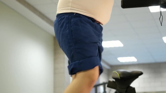 Child big belly walking on treadmill feet close-up Sports Training Equipment at fitness room. fat burning, concept physical culture