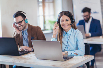 Portrait of happy smiling female customer support phone operator at workplace.