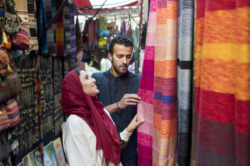 Smiling young muslim couple shopping carpets in a textile store